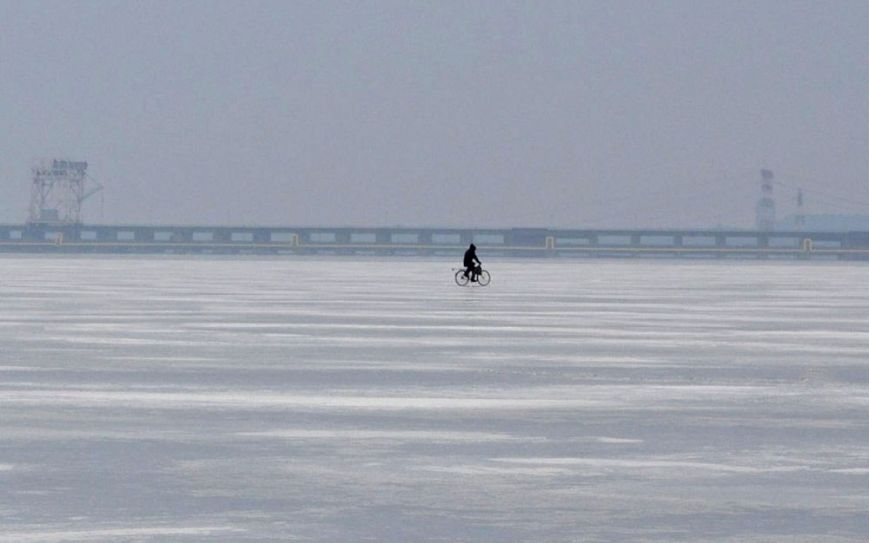 ФОТОФАКТ: В Запорожье мужчина переезжает Днепр на велосипеде